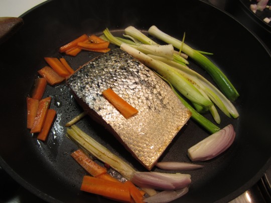 Lachs mit Grünzeug und Möhren zuerst auf der hautlosen Seite anbraten.