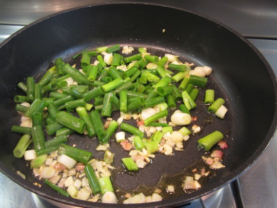 Braten Sie zuerst Zwiebeln, Knoblauch und das Weiße der Frühlingszwiebeln an, dann kommen die grünen Teile und die Chili hinzu.